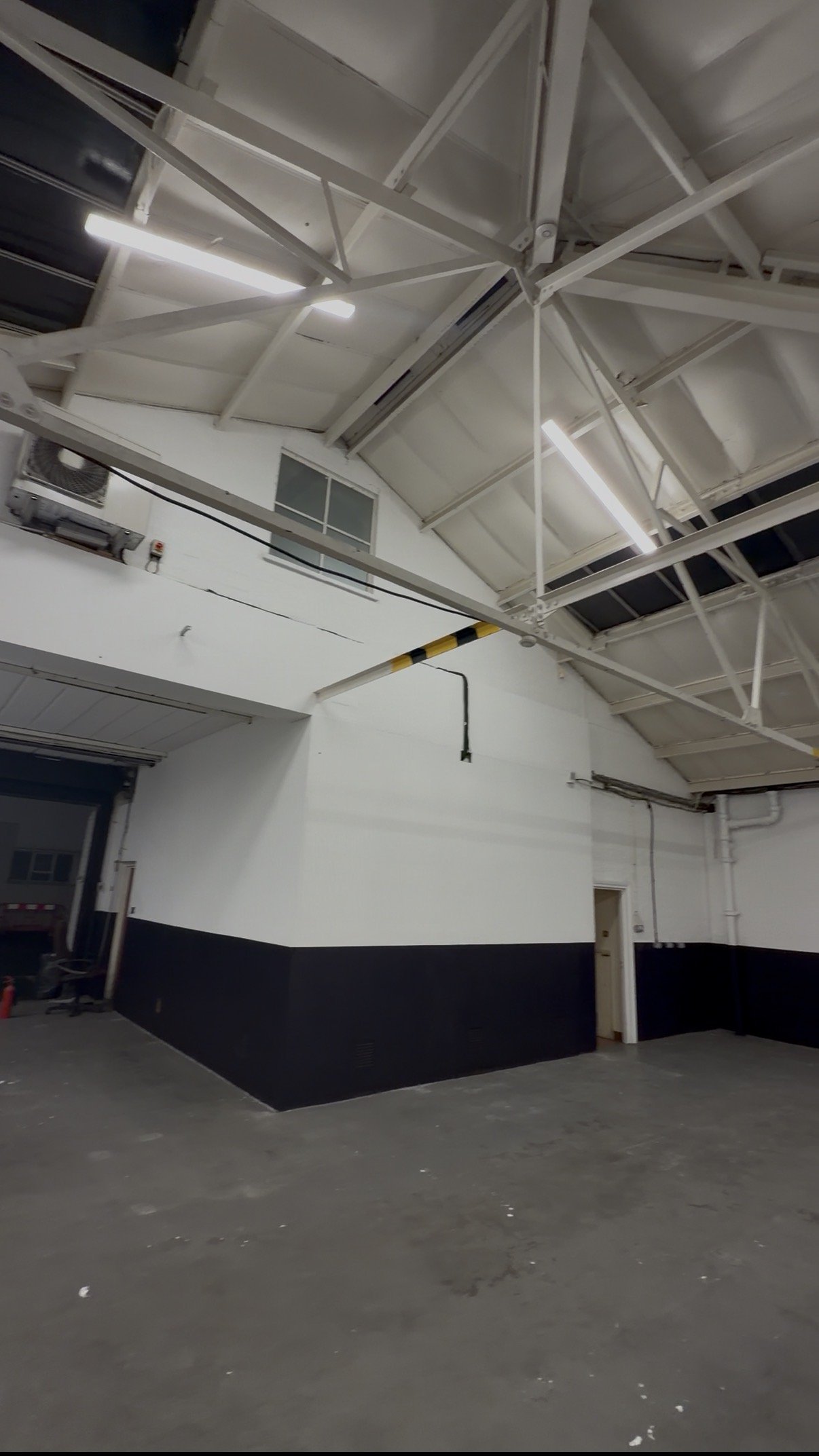 Large industrial workspace with white roof trusses and painted walls.