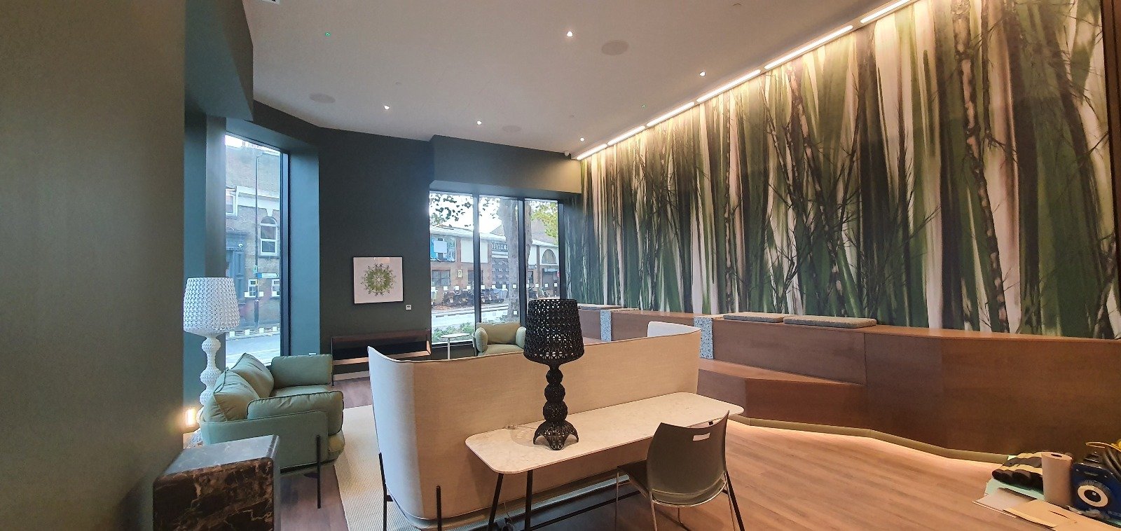 Modern commercial lounge with dark green walls and a forest wall mural.